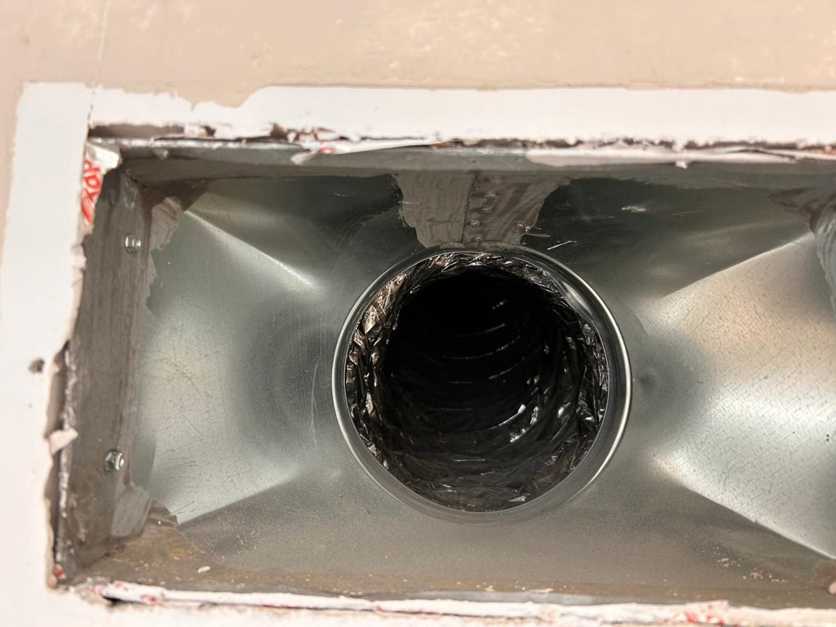 Clean new galvanized vent boot installed in a wall opening